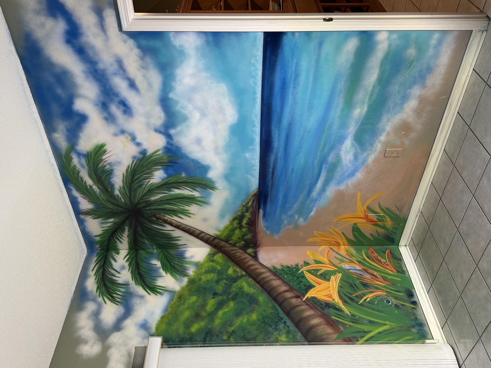 A beach-and-palm feature-wall mural in daylight by Tina Cozart